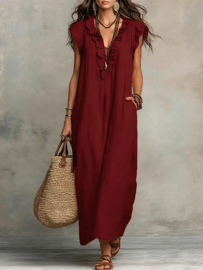 Woman wearing a burgundy dress holding a straw bag against a neutral background