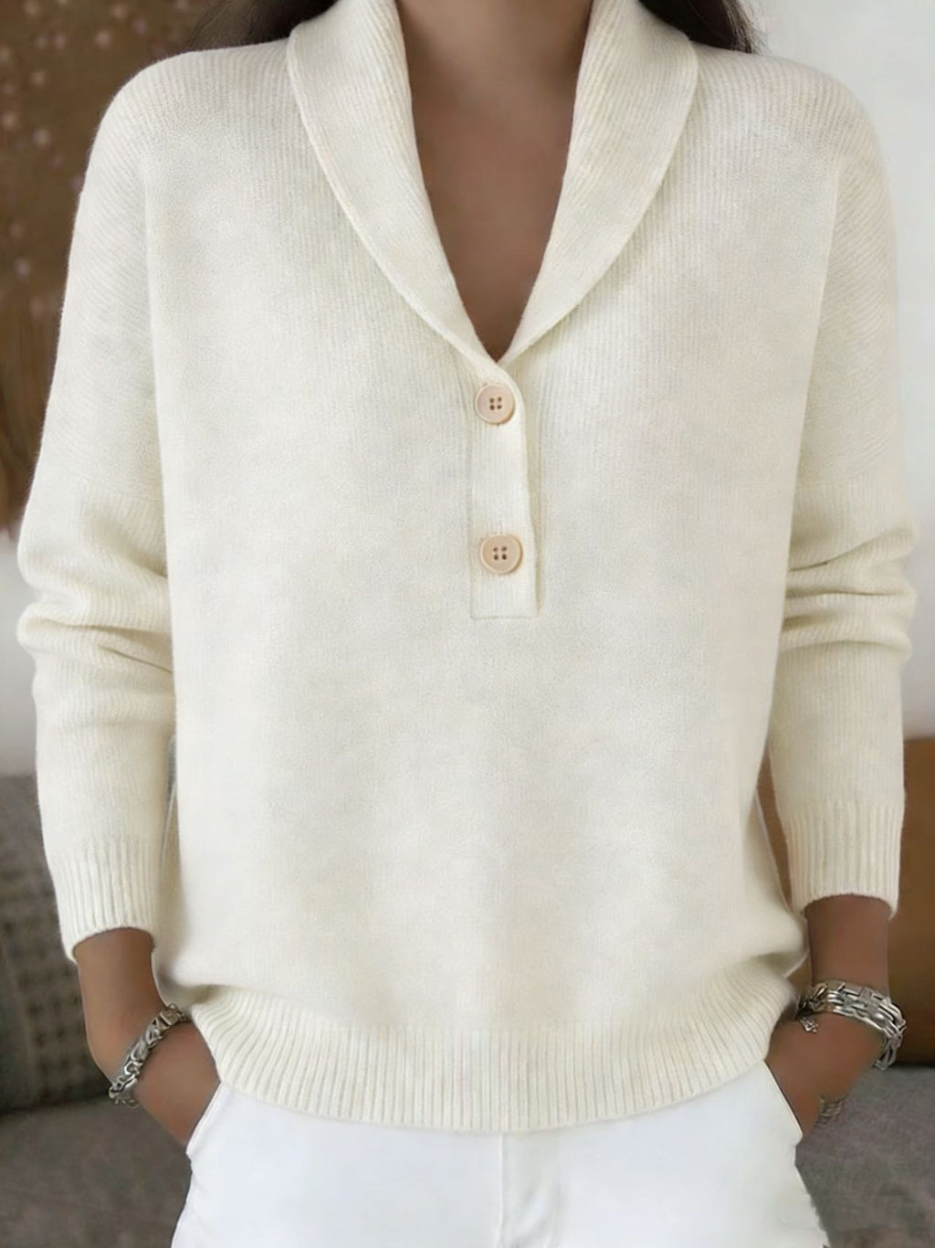 Person wearing a cream-colored sweater with button details.