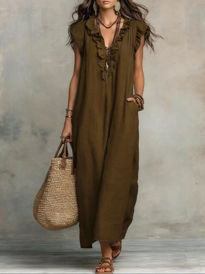 Woman wearing a long olive green dress holding a woven bag against a neutral background