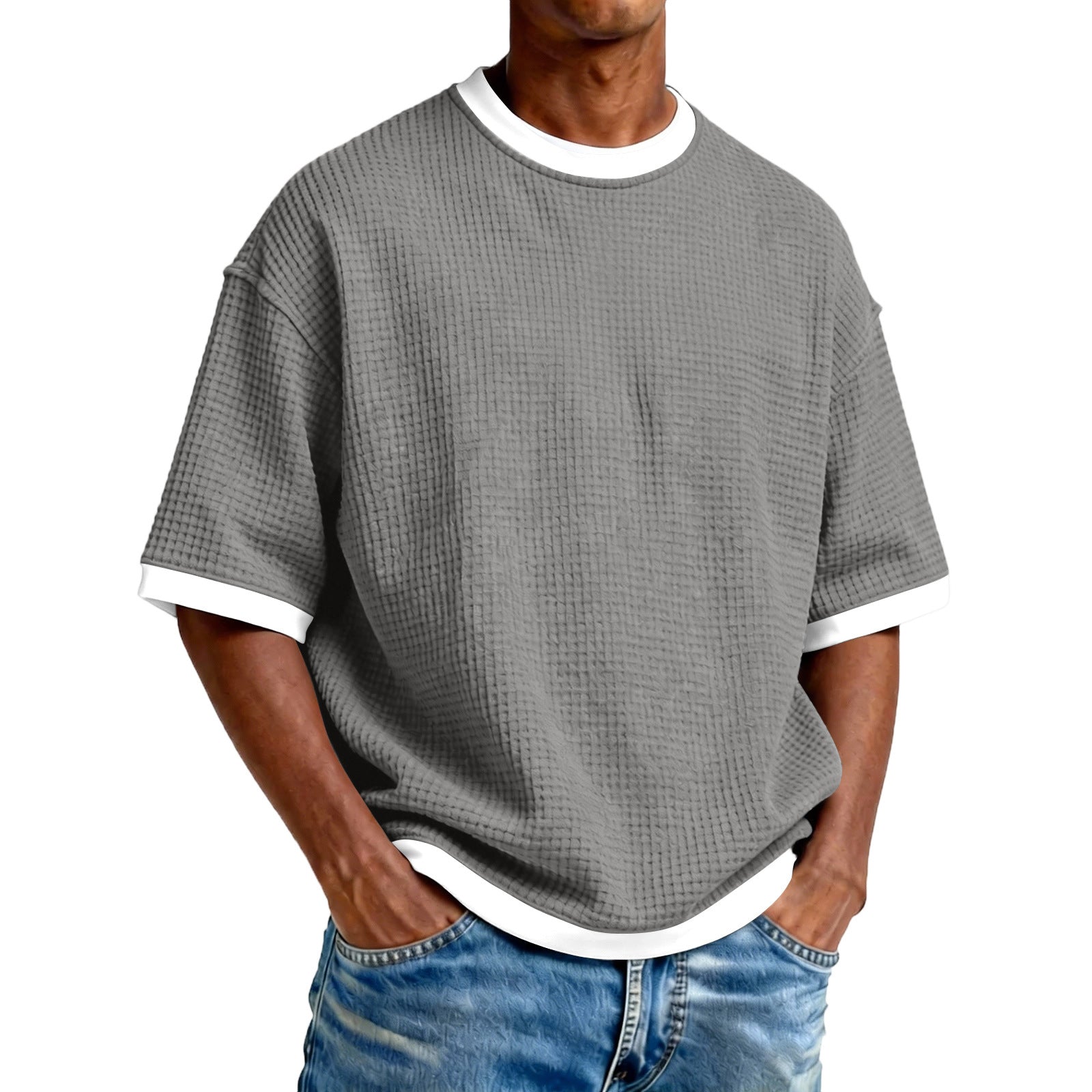 Man wearing a gray textured t-shirt with white trim and blue jeans on a white background