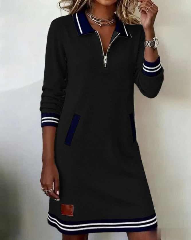 Black dress with white and blue accents worn by a person on a plain background