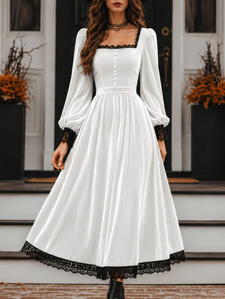 White dress with black lace trim worn by a model on a staircase.