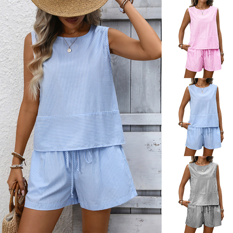 Woman wearing a light blue striped outfit with shorts, standing against a wooden wall.