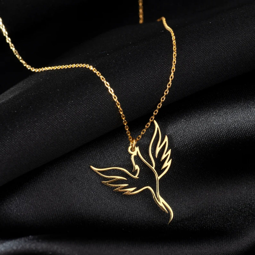 Gold bird-shaped pendant necklace on a black fabric background