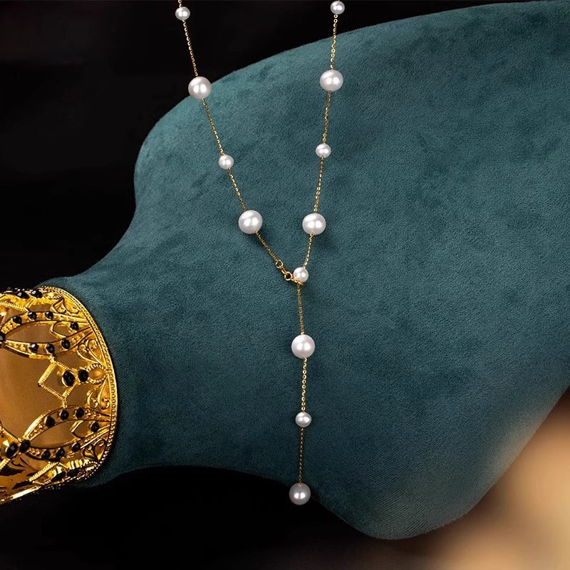 Pearl necklace draped over a teal cushion with a gold decorative element.