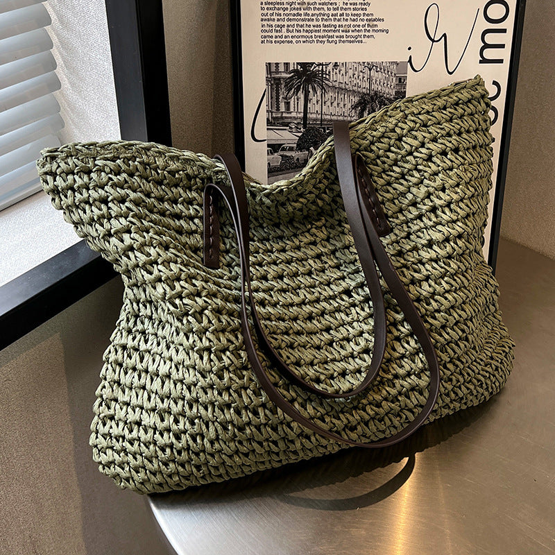 Green woven handbag with a brown strap on a wooden surface.