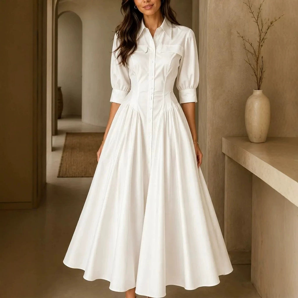 Woman wearing a white dress in an indoor setting with a vase on a shelf.