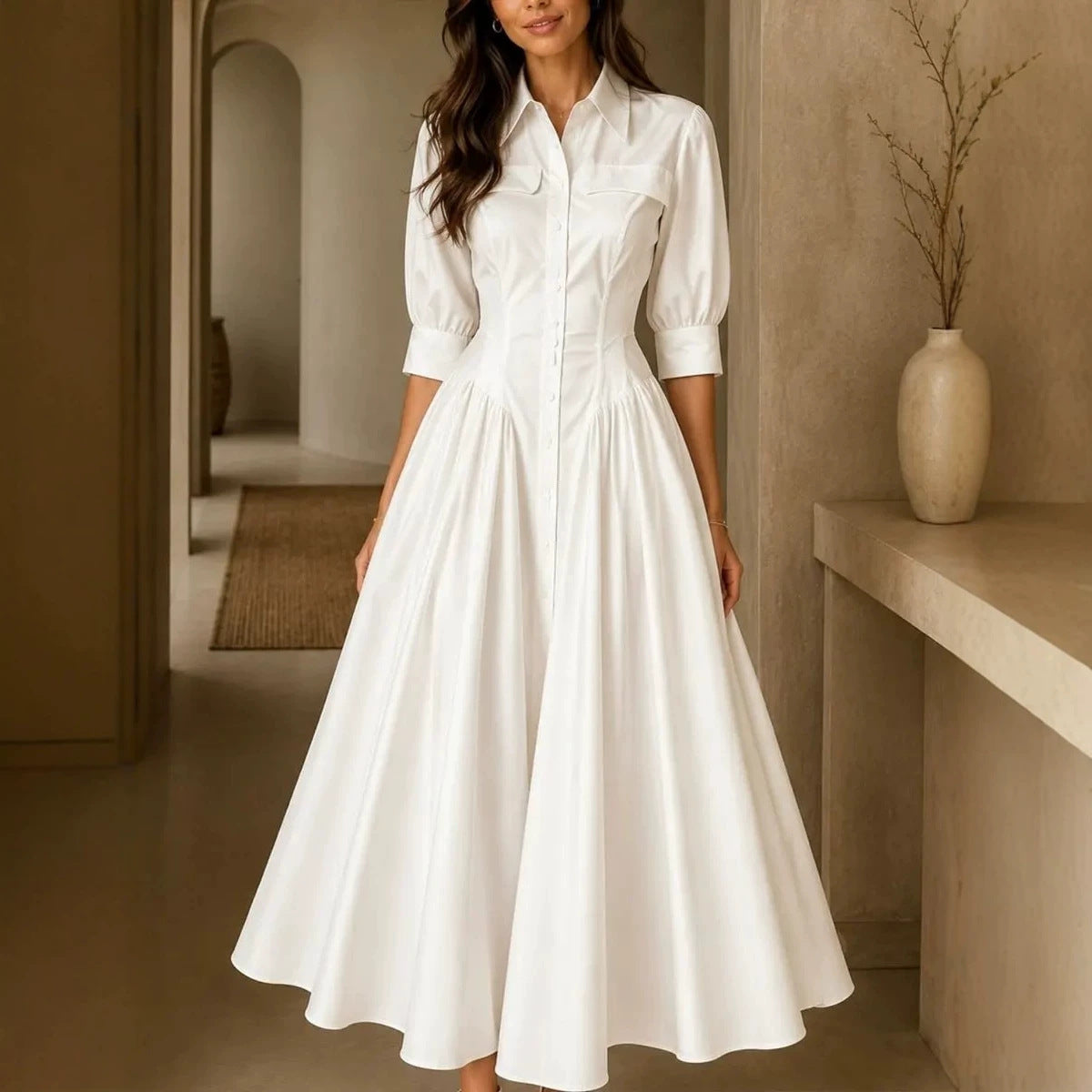 Woman wearing a white dress in an indoor setting with a vase on a shelf.