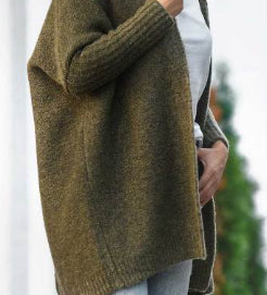 Person wearing a brown knitted cardigan with a blurred background
