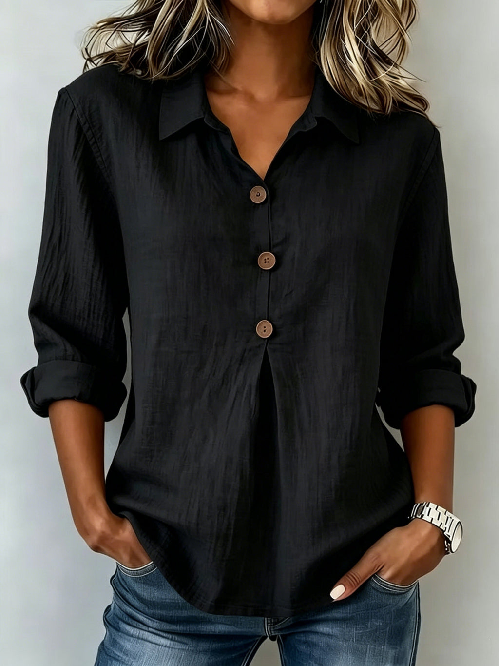 Person wearing a black button-up shirt and blue jeans against a plain background