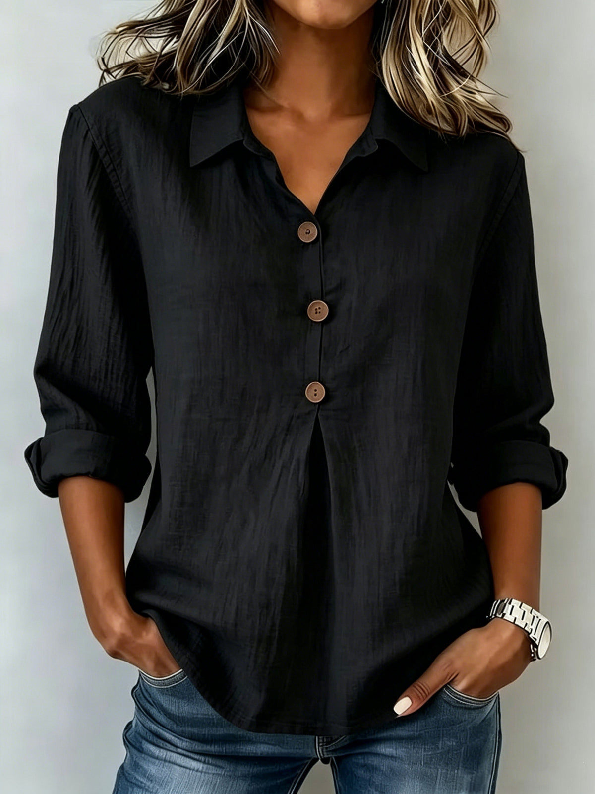 Person wearing a black button-up shirt and blue jeans against a plain background