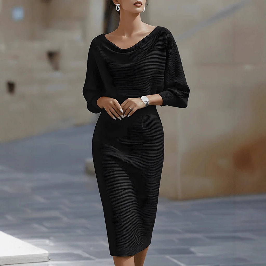 Woman wearing a black dress standing on a stone pavement.
