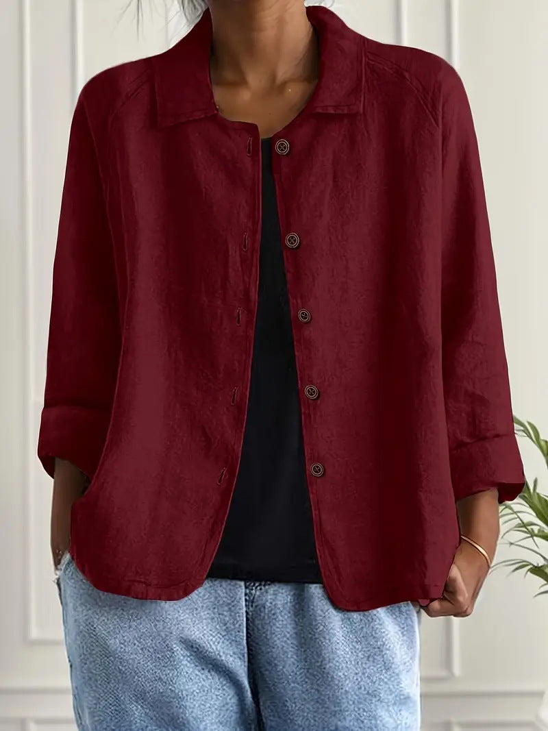 Person wearing a red jacket over a black shirt and blue jeans indoors.
