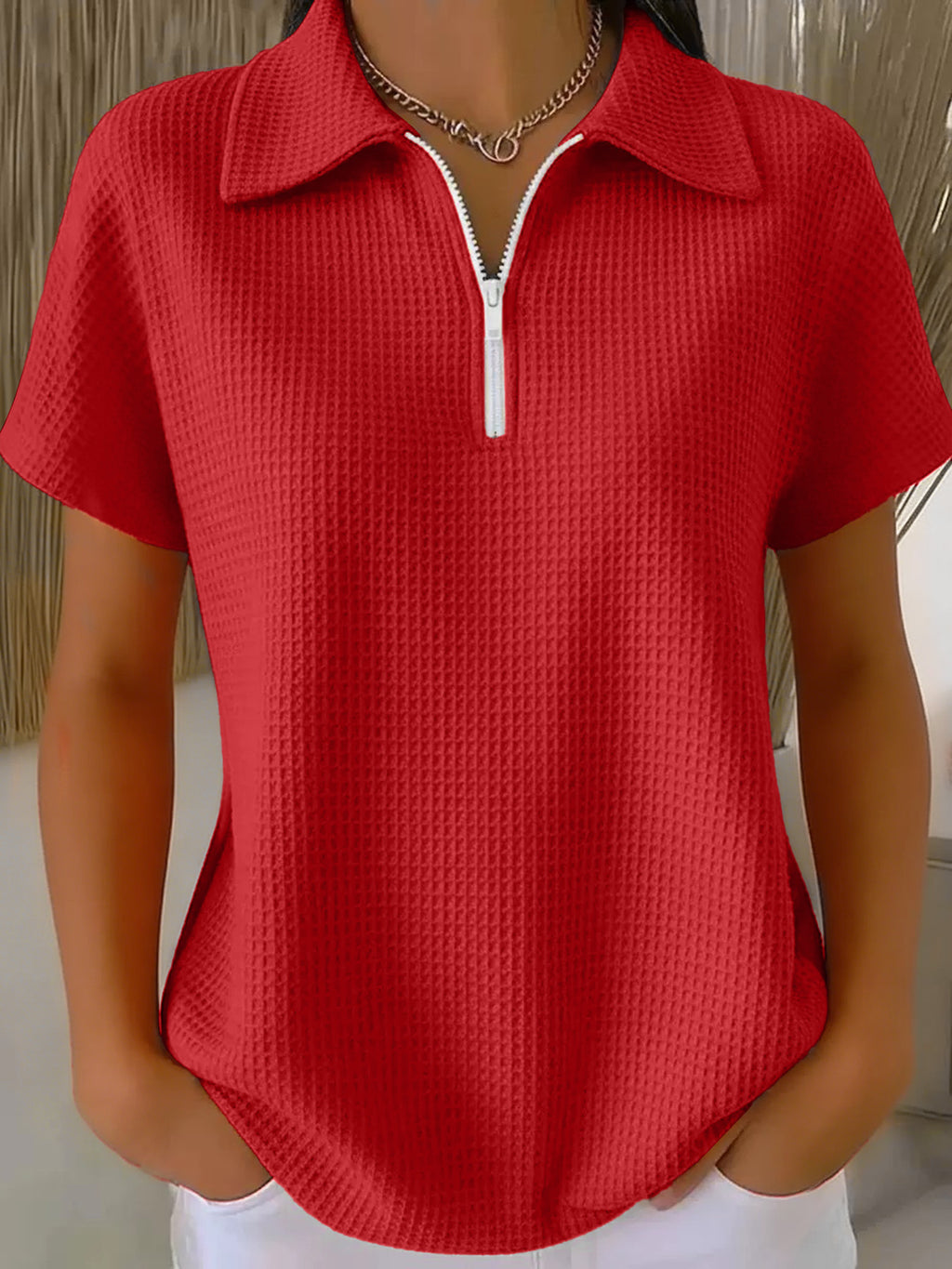 Red textured short-sleeve top with a zipper on a mannequin against a neutral background