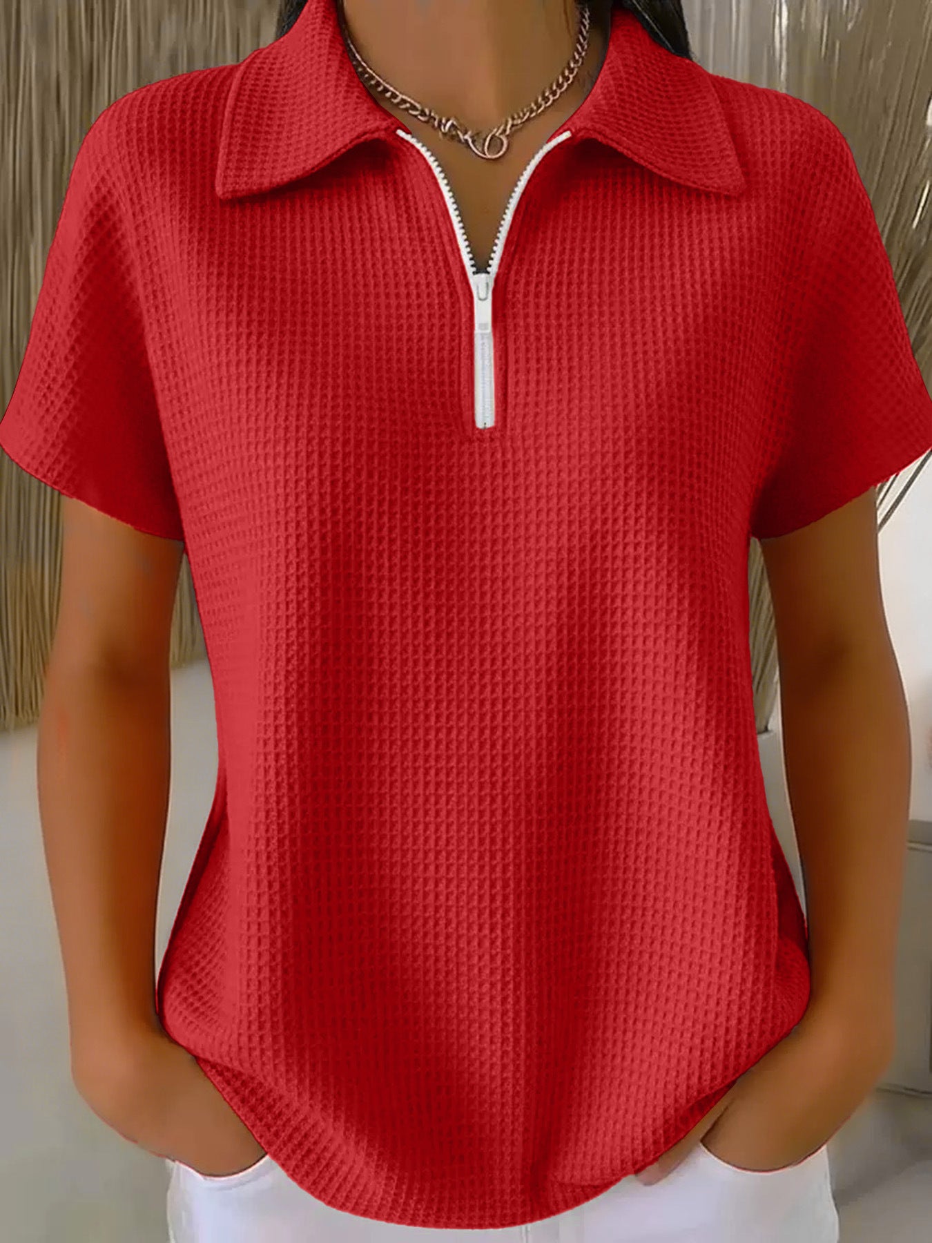 Red textured short-sleeve top with a zipper on a mannequin against a neutral background