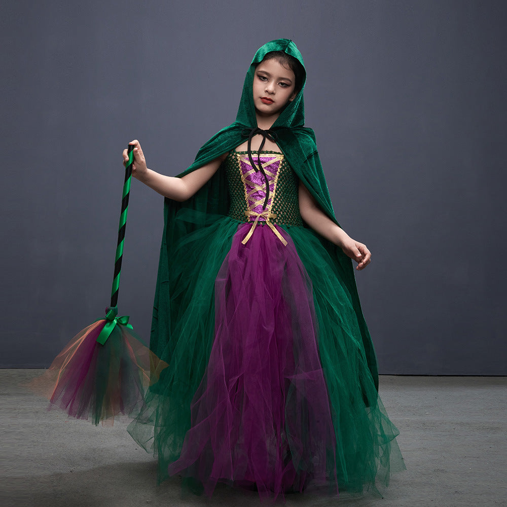 Child in a green and purple costume with a hood, holding a broom against a gray background