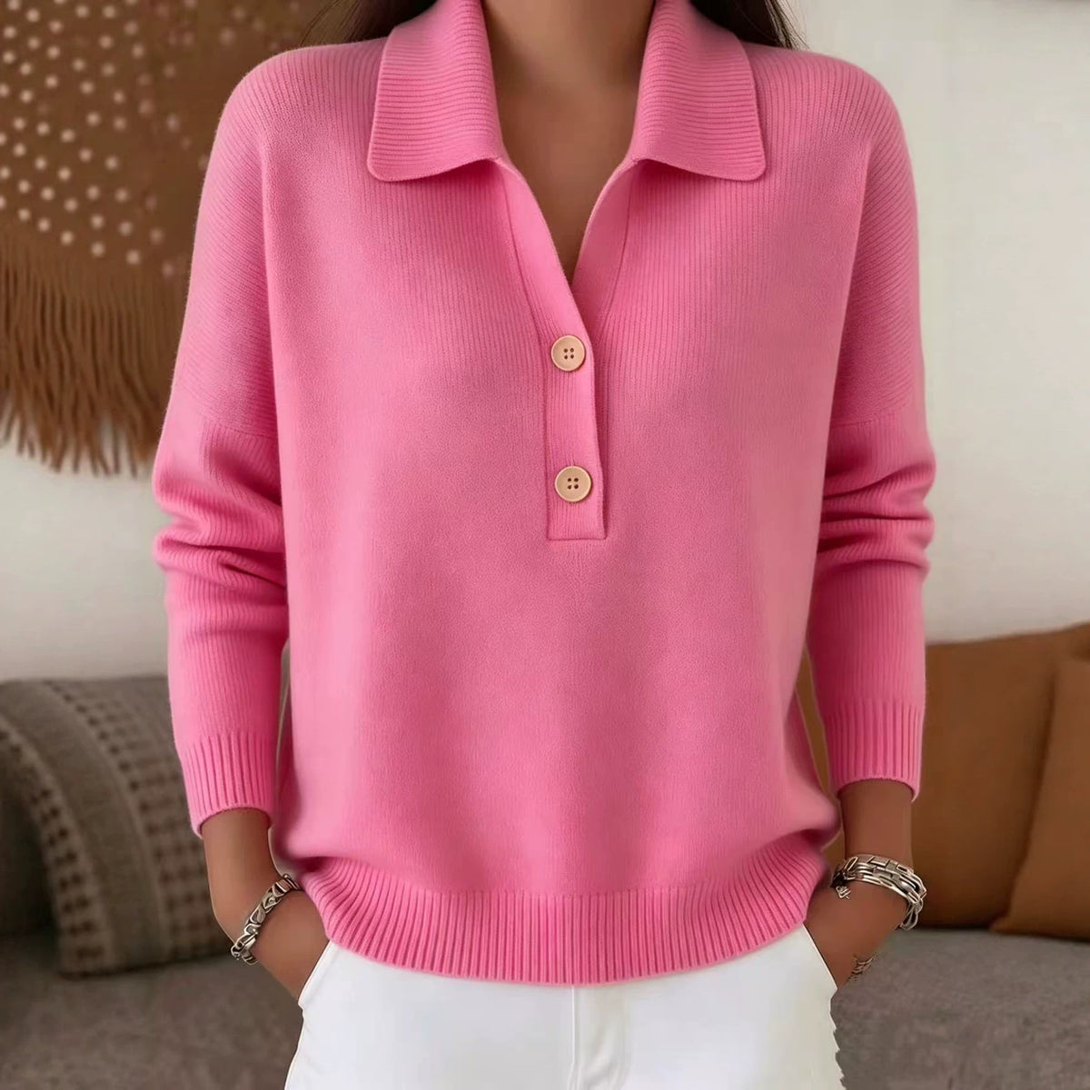 Person wearing a pink sweater with a collar and buttons, sitting on a couch.