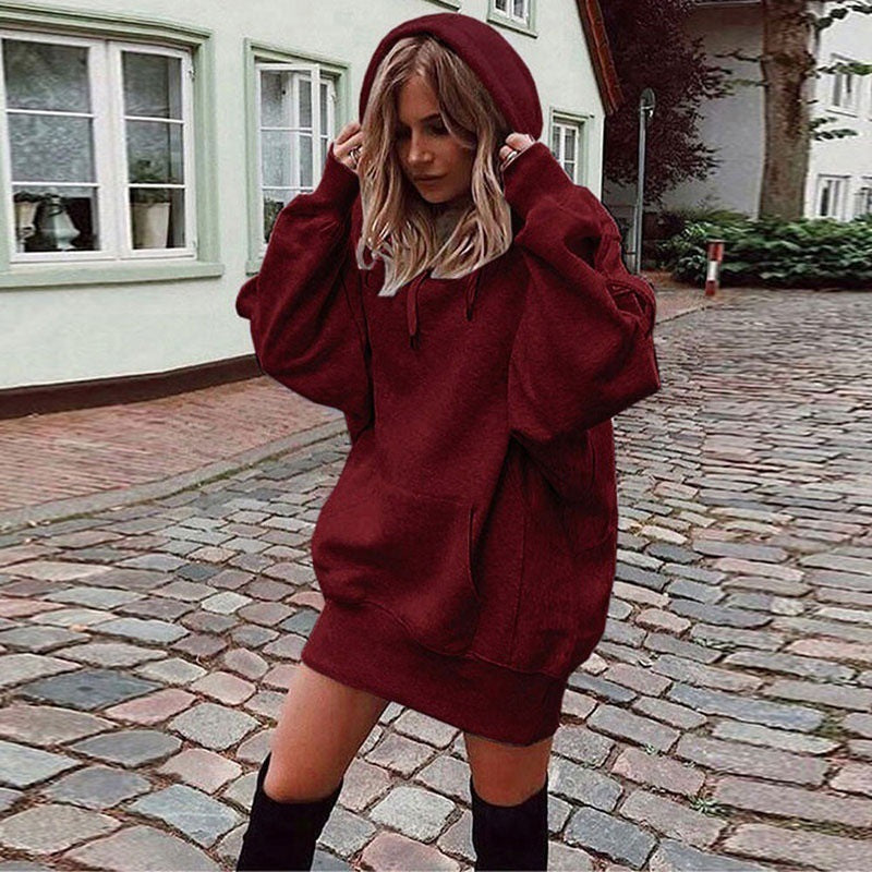 Person wearing a burgundy hoodie dress on a cobblestone street.
