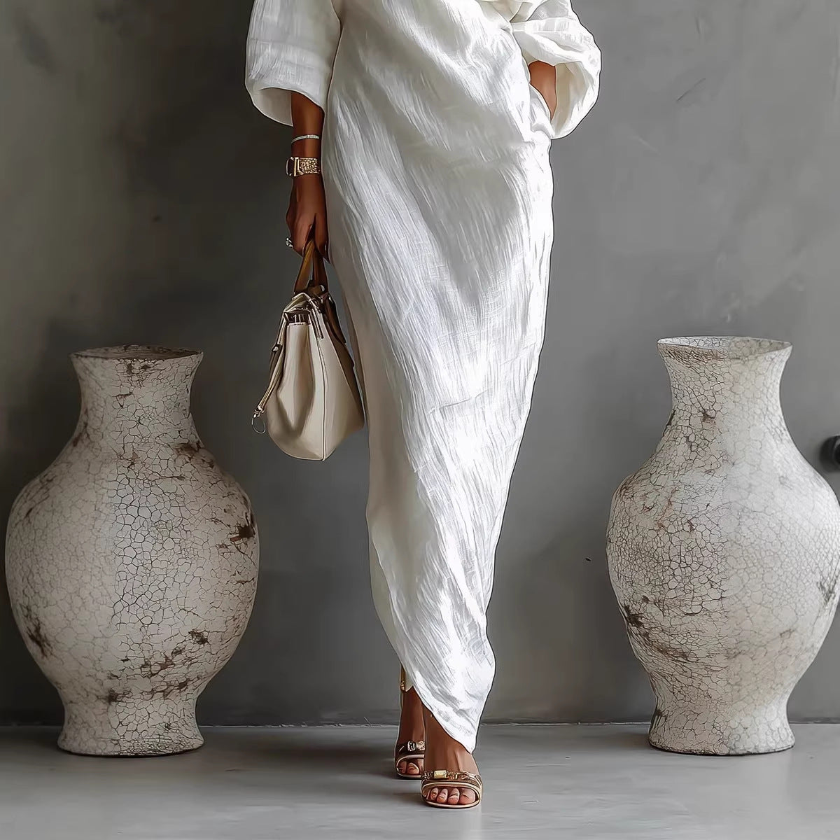 Person in a white outfit standing between two large, textured vases against a gray background