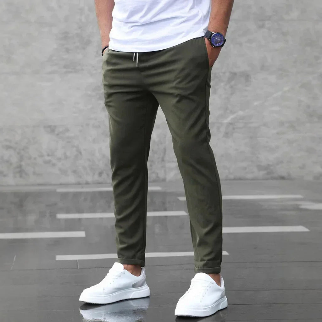 Person wearing olive green pants and white sneakers on a gray floor.