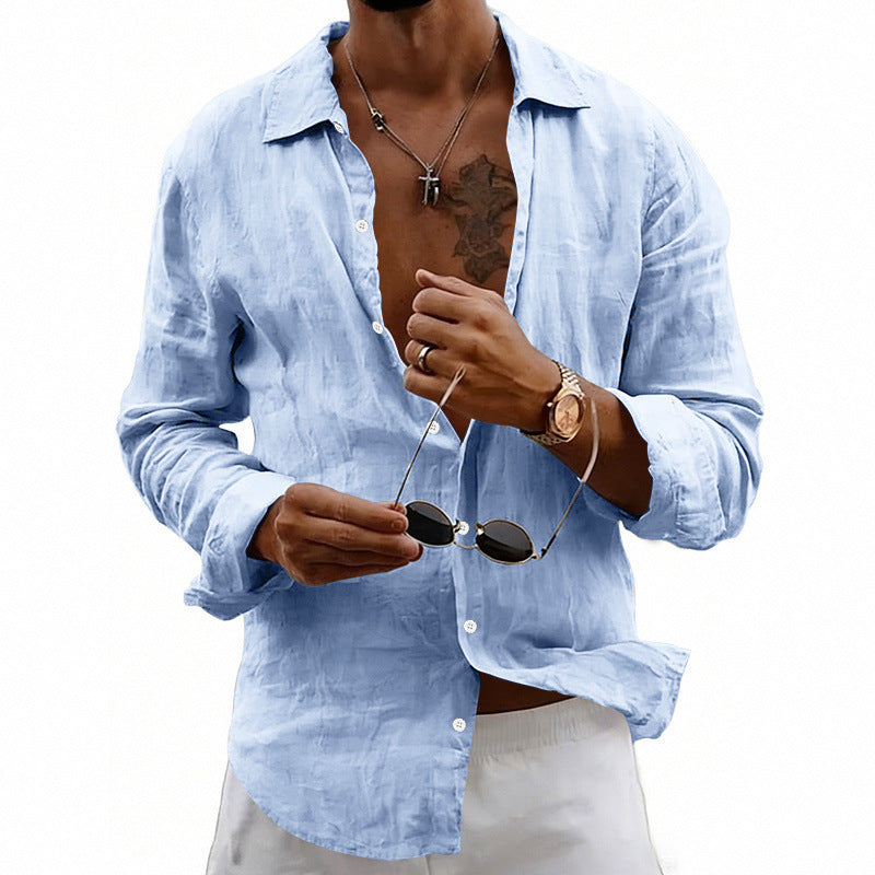 Man wearing a light blue shirt with rolled-up sleeves, holding sunglasses, on a white background