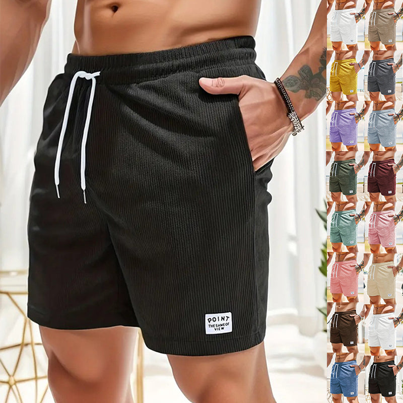 Black shorts with a brand logo displayed on a person, with multiple color options shown in the background.