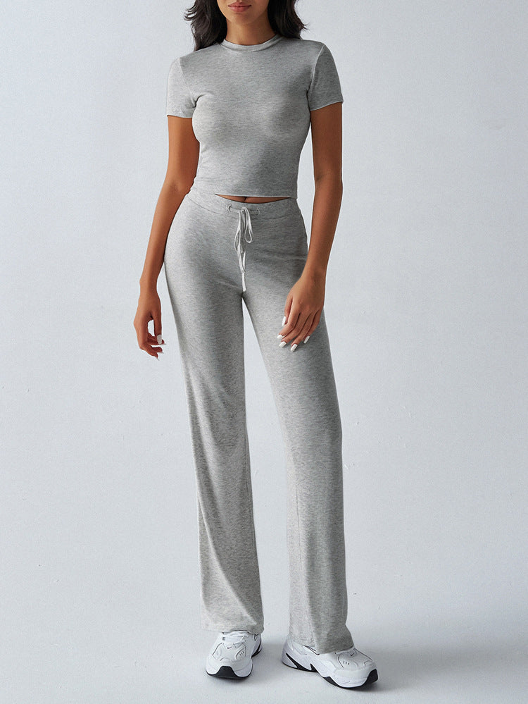 Person wearing a gray matching set with a top and pants on a white background