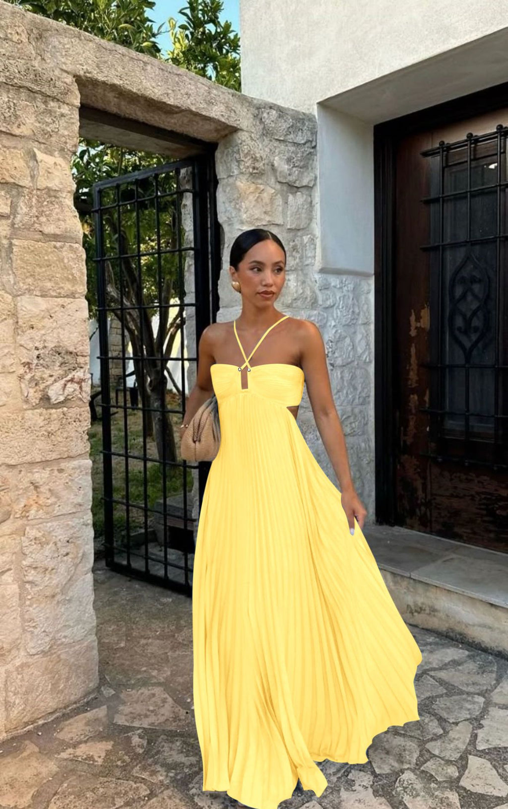 Woman in a yellow dress standing in front of a stone building.
