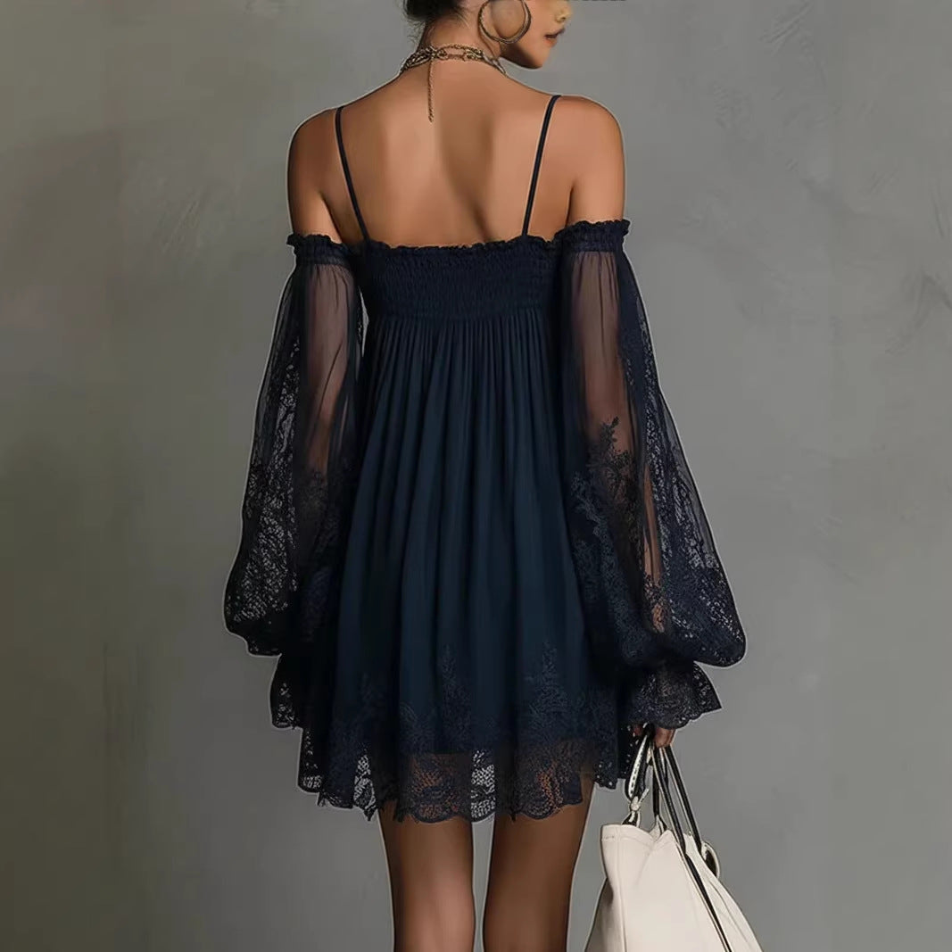 Woman wearing a dark blue dress with sheer sleeves against a gray background