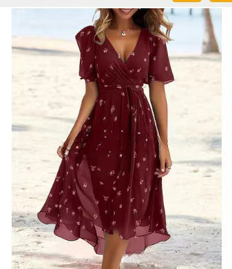 Woman wearing a burgundy floral dress on a beach.