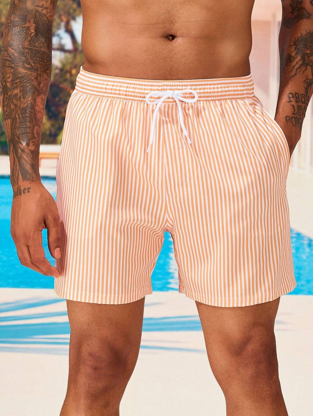Person wearing striped swim shorts with a pool in the background