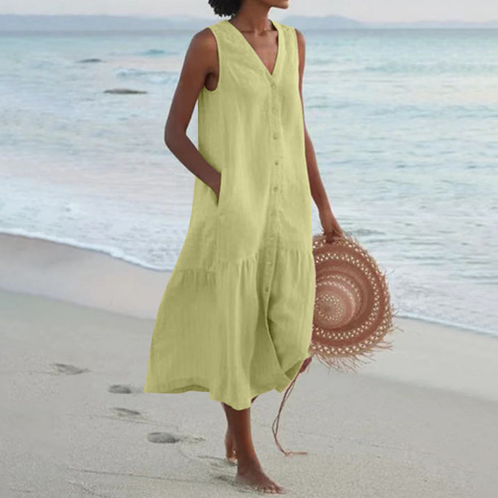 Woman in a yellow dress holding a straw hat on a beach