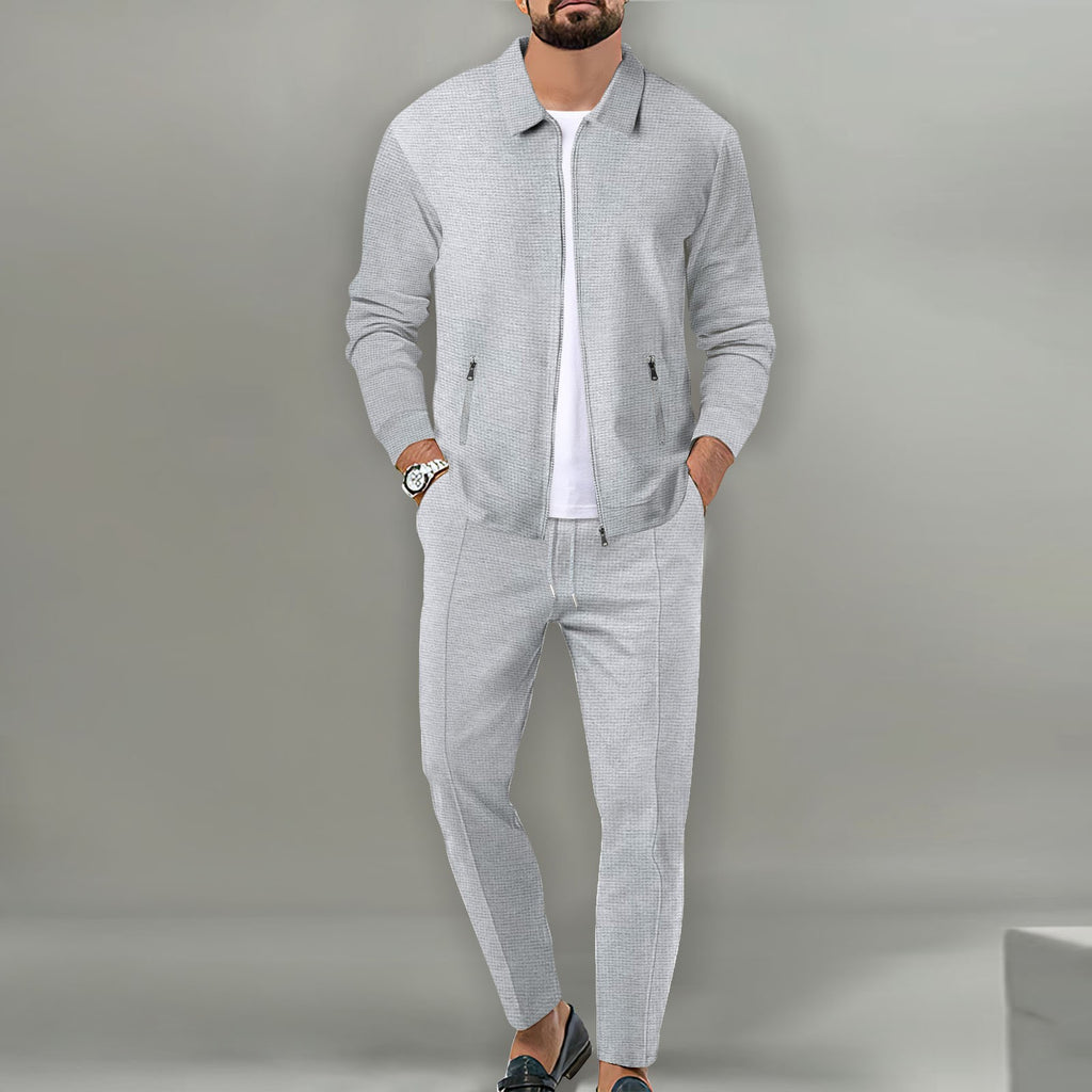 Man wearing a gray tracksuit against a plain background