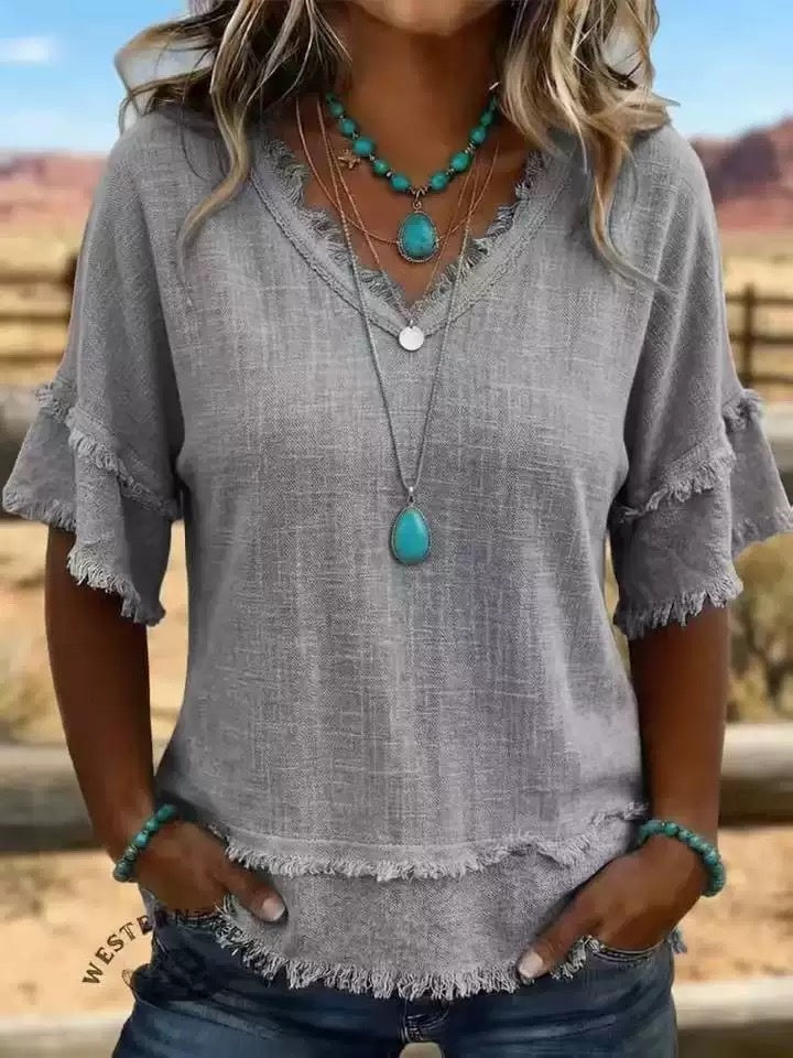 Woman wearing a gray blouse with frayed edges and turquoise jewelry in a desert setting