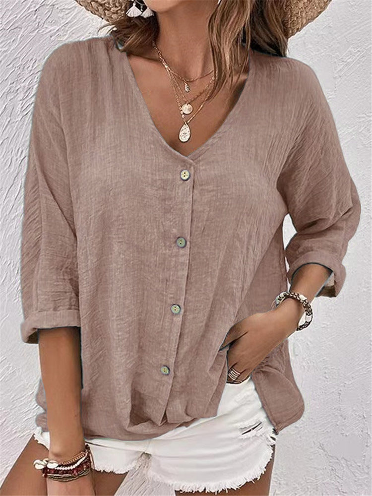 Woman wearing a brown button-up shirt and white shorts against a light background