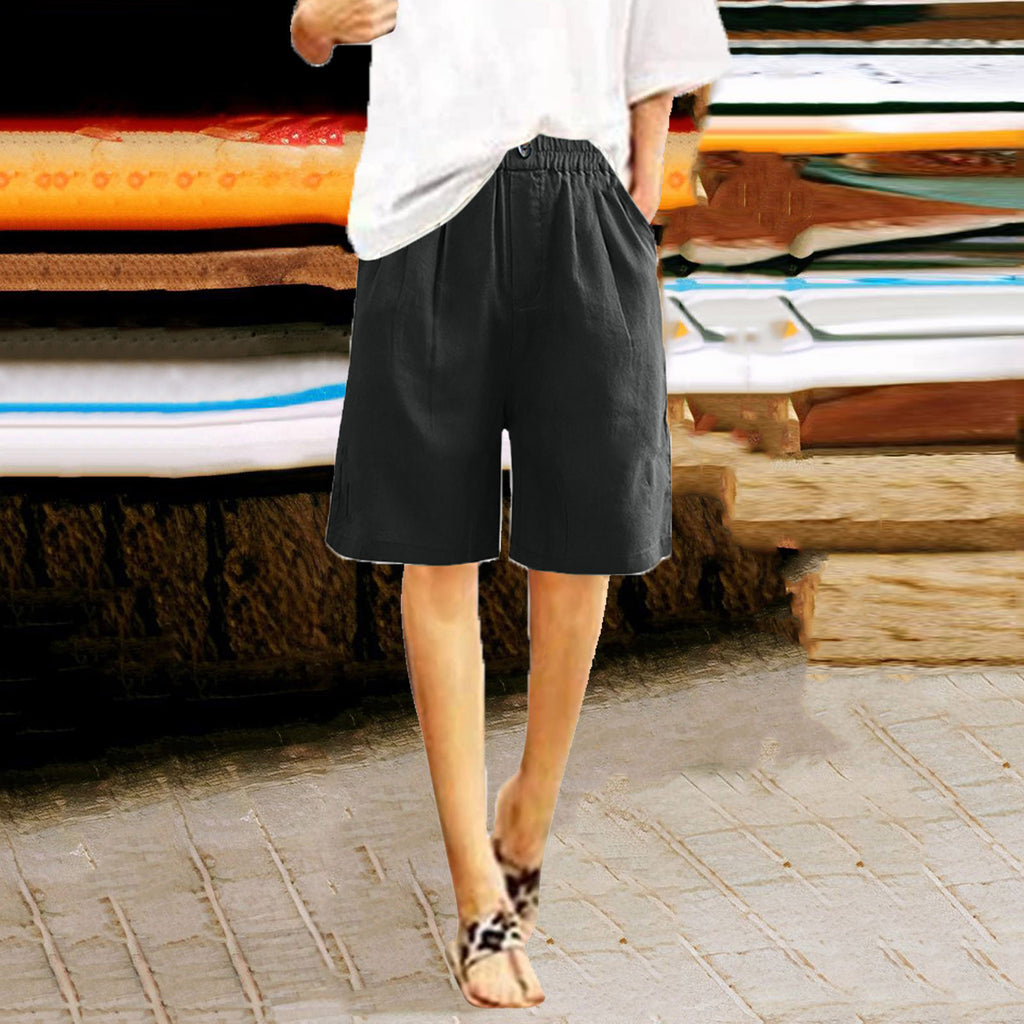 Person wearing black shorts standing in front of stacked surfboards.