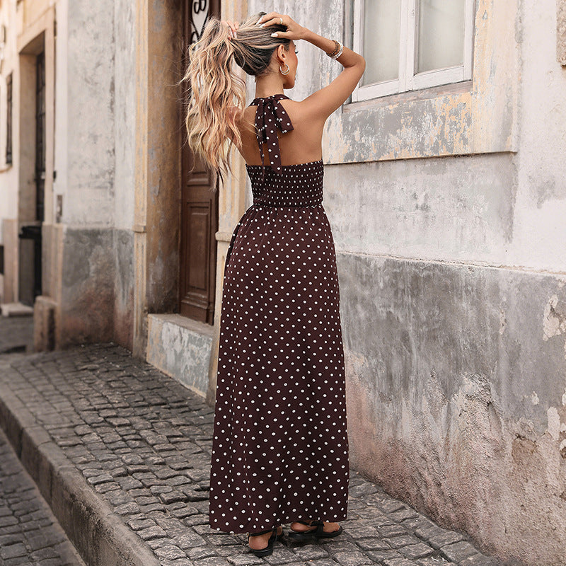 Woman in a polka dot dress standing on a street with old buildings.