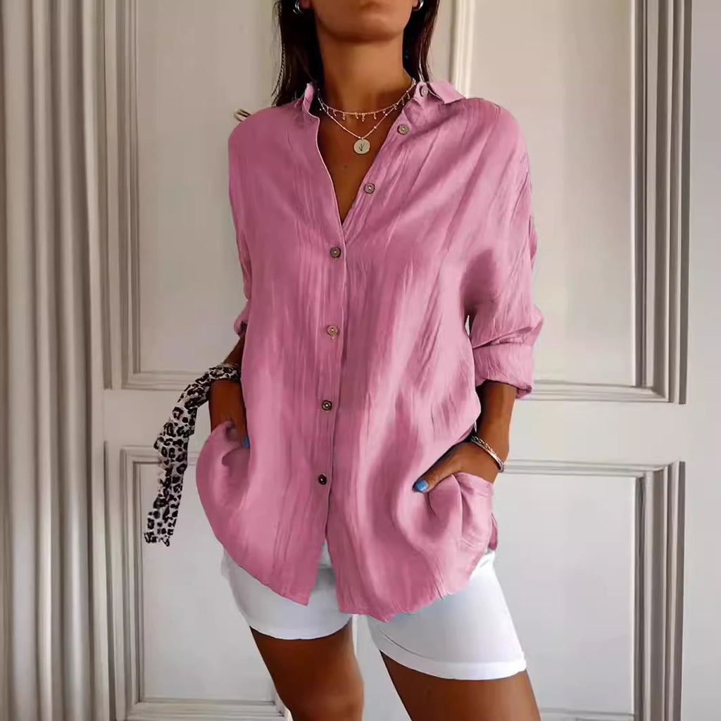 Person wearing a pink button-up shirt and white shorts against a neutral background