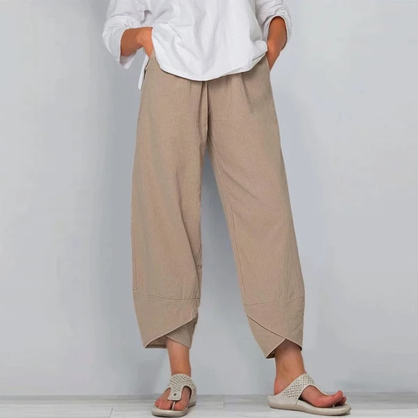 Person wearing beige wide-leg pants and a white shirt against a plain background