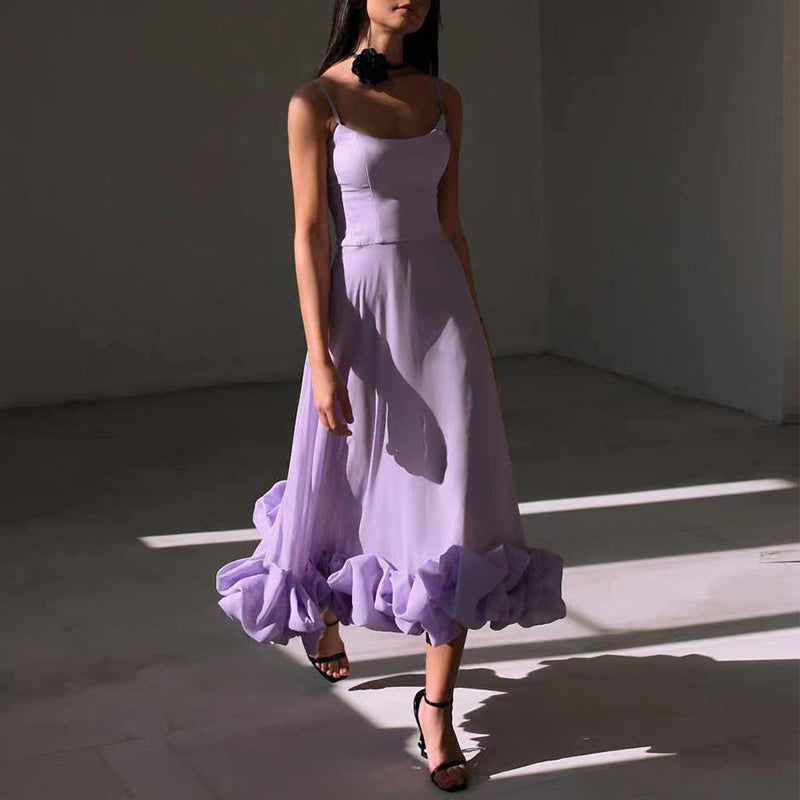 Woman wearing a long purple dress standing in a sunlit room with shadows on the floor.