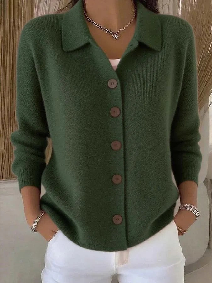 Green cardigan with brown buttons worn by a person, against a neutral background