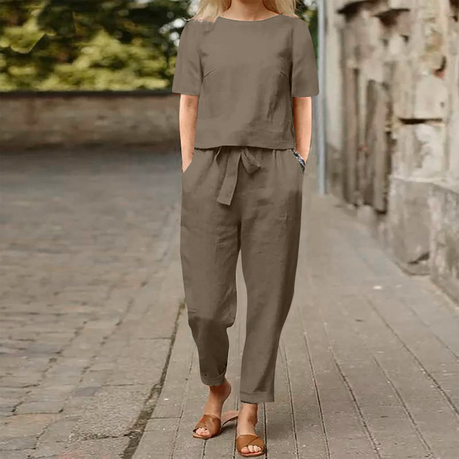Person wearing a brown outfit standing on a stone path with a blurred background