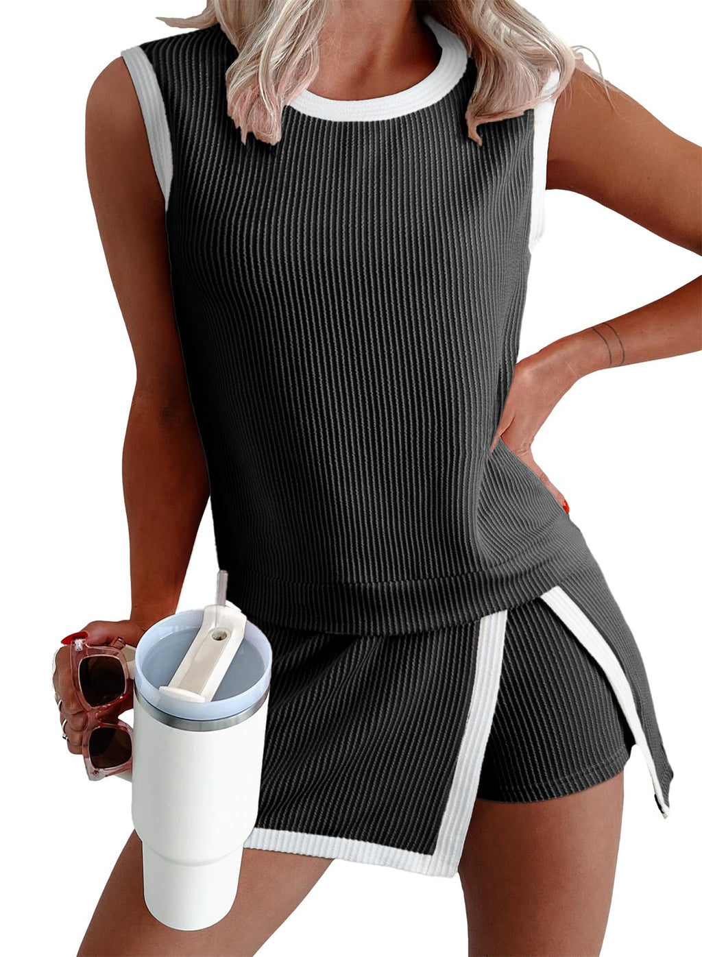 Woman wearing a black sleeveless top and shorts with white trim, holding a white cup with a blue lid.