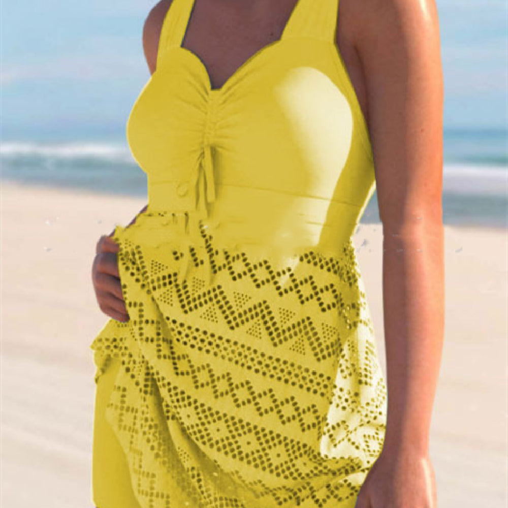Person wearing a yellow dress with cut-out details on a beach.