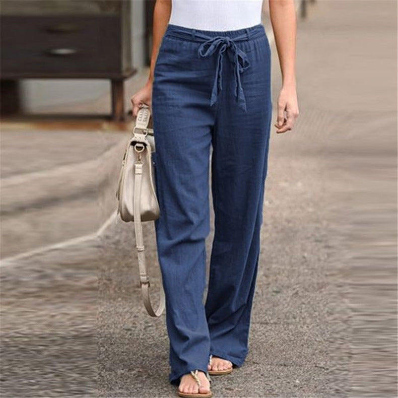 Person wearing blue pants holding a beige handbag on a blurred background