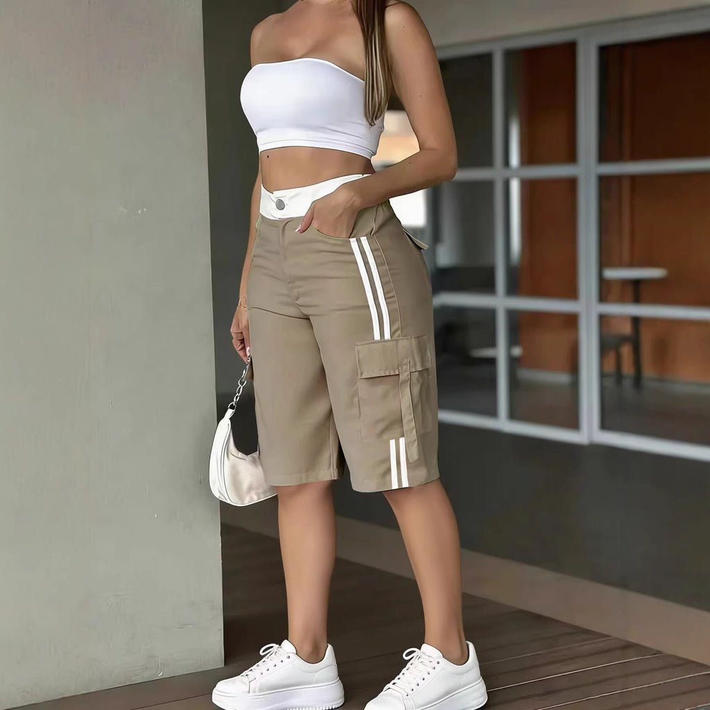 Person wearing a white crop top and beige cargo shorts with white stripes, standing indoors.