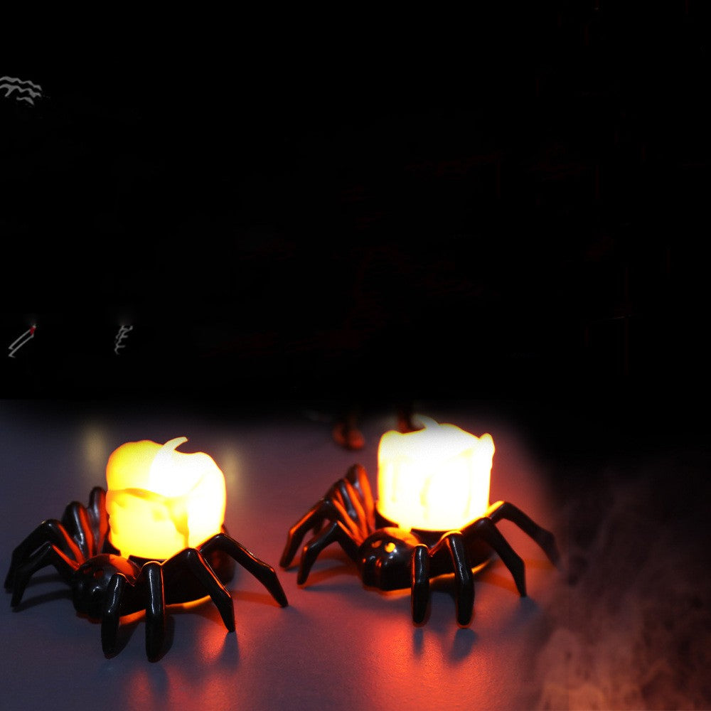 Two spider-shaped candle holders with glowing candles on a dark background
