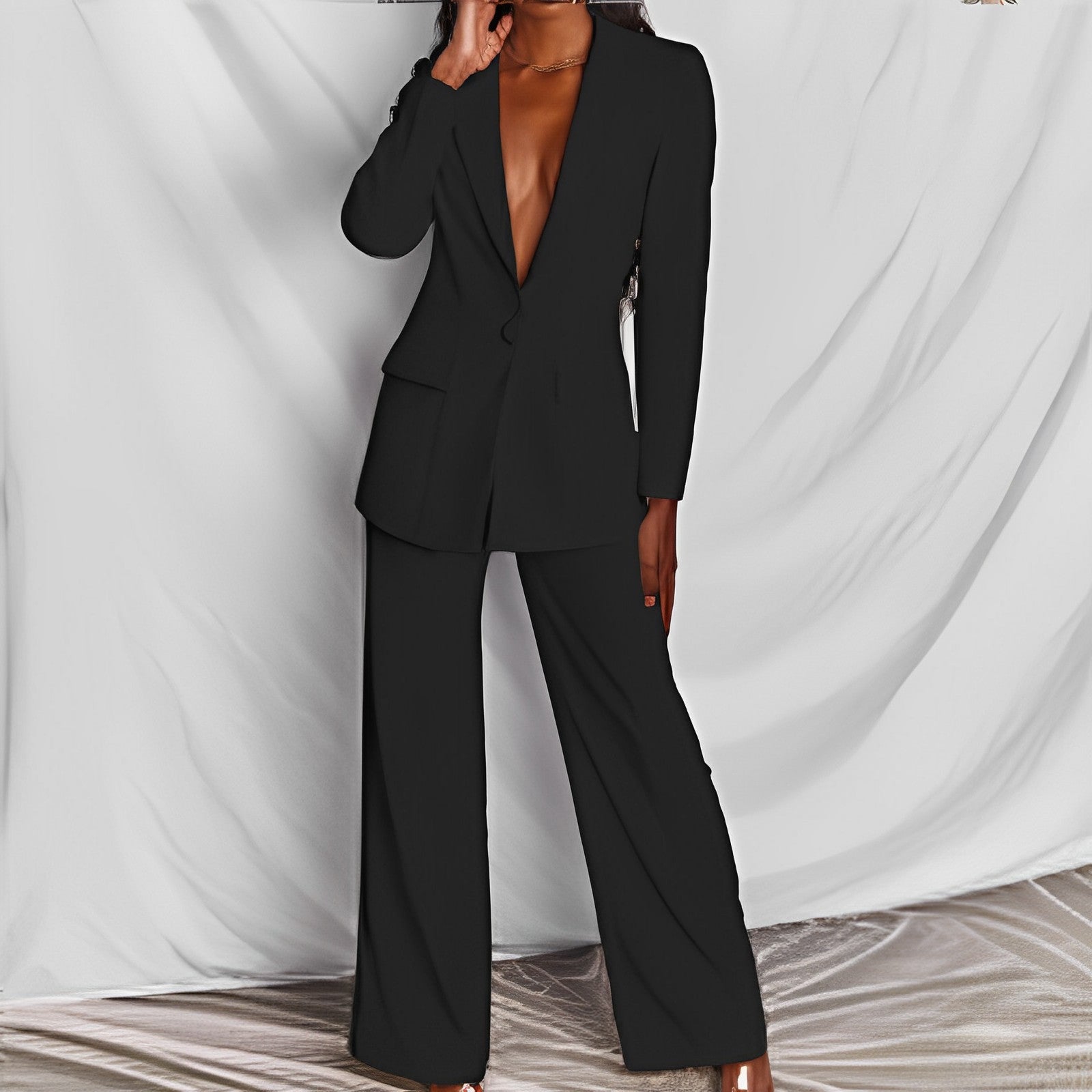 Black suit worn by a model against a white draped curtain background