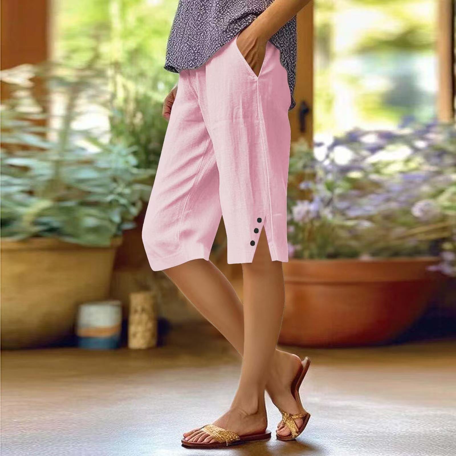 Person wearing pink shorts with buttons, standing indoors with plants in the background