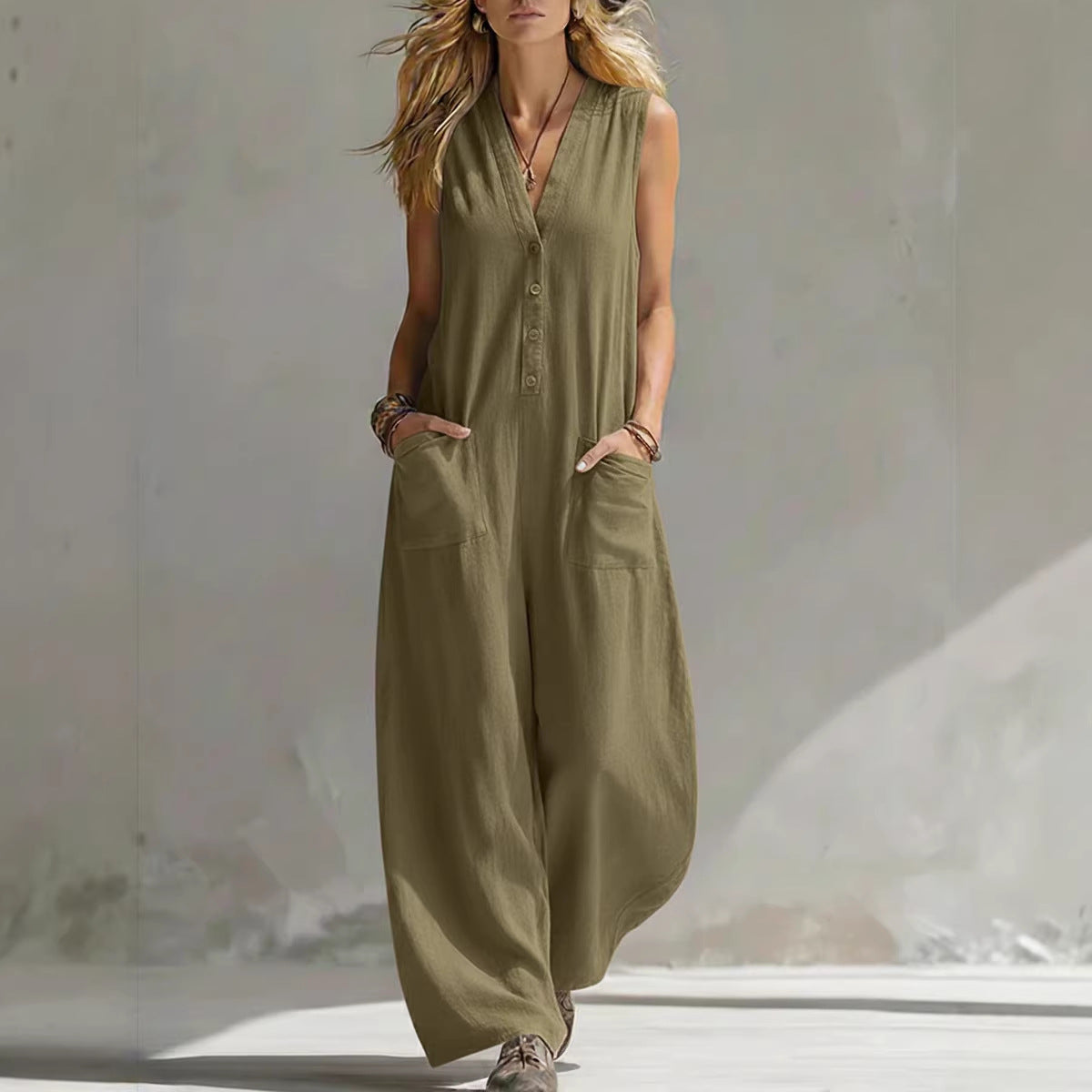 Woman wearing a sleeveless olive green jumpsuit against a neutral background